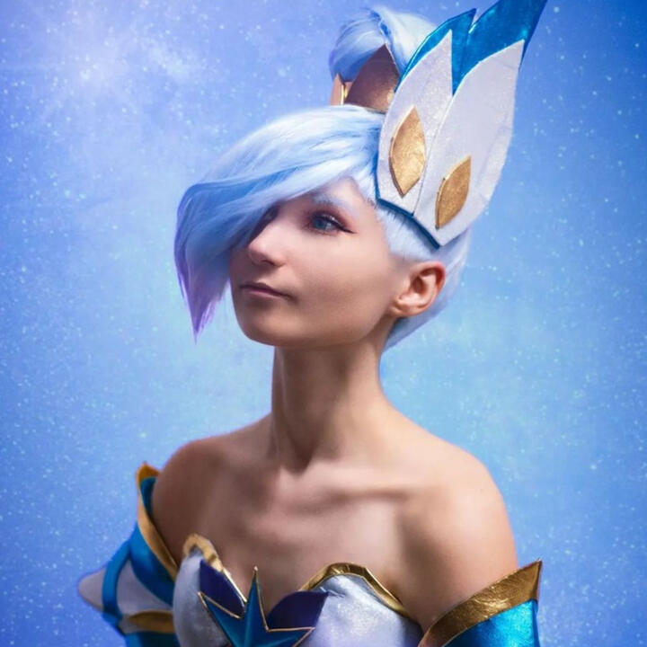 Seiko is standing facing camera at an angle, she is looking upwards with her hands clasped together at a chest line. She is dressed in her handmade star Guardian Orianna cosplay